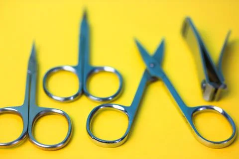 Set of sharp steel manicure scissors and spikes isolated on the yellow surfac 写真素材