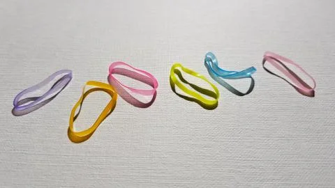Set of small multi-colored elastic bands for hair on a white table. Fotos Stock