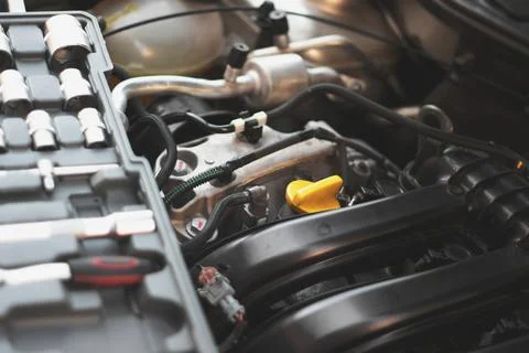 A set of socket wrenches lies on the internal combustion engine of a car in t Stock Photos