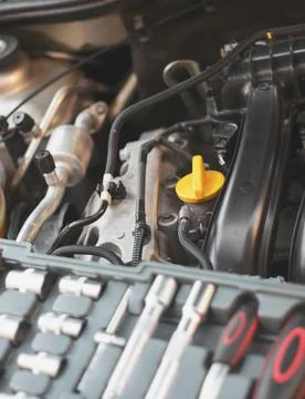 A set of socket wrenches lies on the internal combustion engine of a car in t Stock Photos