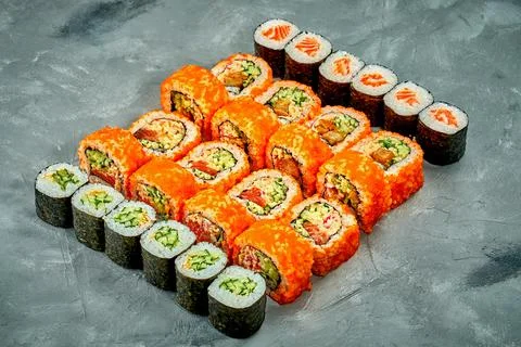 Set of sushi rolls and maki rolls with different fillings on a gray backgroun Stock Photos