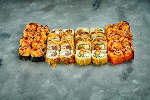Set of sushi rolls with different fillings on a gray background. Selective Fo Stock Photos