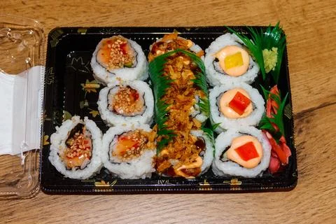 Set of sushi rolls in plastic box on wooden table Stock Photos