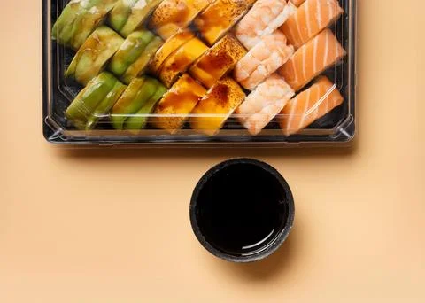 Set of sushi rolls in plastic packages on a light background, top view. Stock Photos