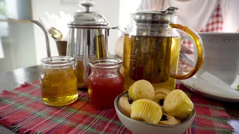 Set for tea drinking. Tea pot, honey, jam, cakes. Woman with cup on background. Stock Footage 88662284