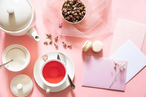 Set of tea preparation featuring rose buds, elegant teapot, pastel macaron, and Stock Photos