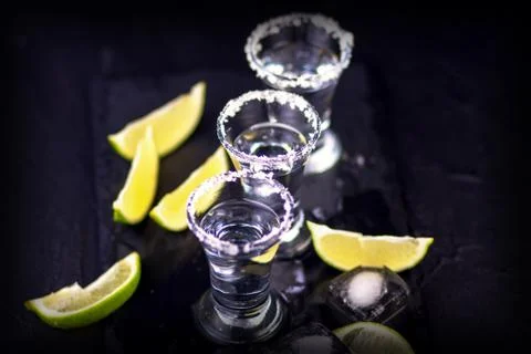 Set of tequila shots on a dark wooden background with de-focused back Stock Photos