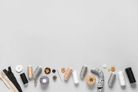 Set of thread spools with measuring tape and sewing supplies on grey backgrou 写真素材