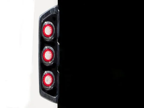 A set of three circular rear red brake stop lights on a white vehicle with black Stock Photos