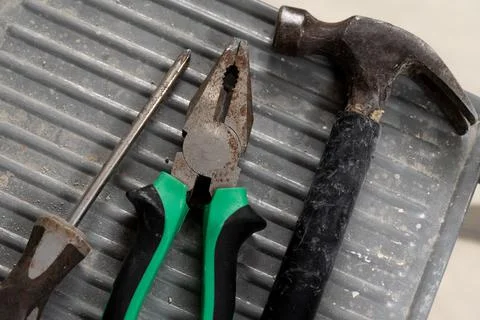 Set of three construction tools on a ladder hammer, pliers and screwdriver. Stock Photos