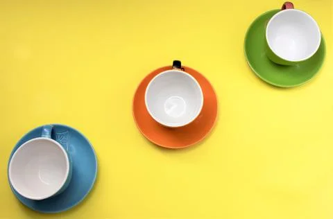 A set of three diagonal ceramic cups with handles on a yellow background Stock Photos