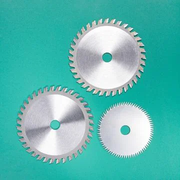 Set of three discs with carbide teeth for a table saw on a green background Stock Photos