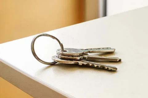 Set of three house keys on the ring on table in a room. Stock Photos