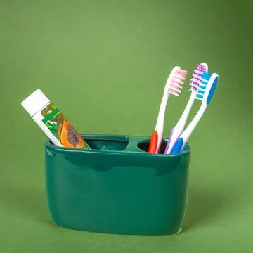 A set of three multi-colored toothbrushes, a tube of eco-friendly toothpaste Stock Photos