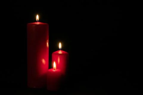 Set of three red candles burning in the dark Stock Photos