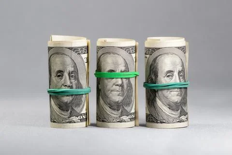 A set of three rolls of hundred-dollar bills stretched with an elastic band.  Stock Photos