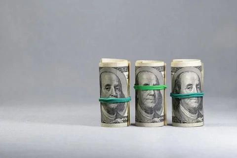 A set of three rolls of one hundred dollar bills tied with an elastic band .. Stock Photos