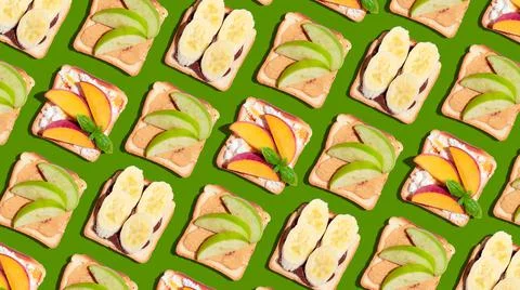 Set of toasted bread with peach, apple and banana on green background. Stock Photos