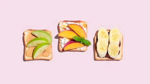 Set of toasted bread with peach, apple and banana on pink background. Stock Photos