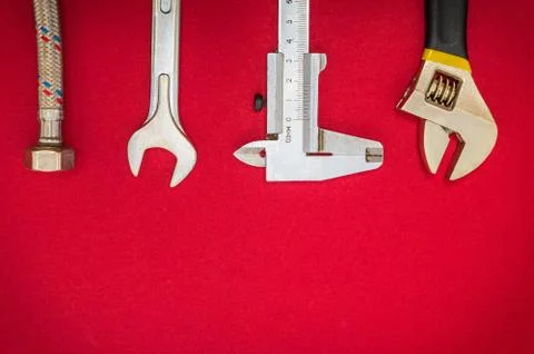Set of tool and hose for plumbers on red background with space for advertisin Stock Photos