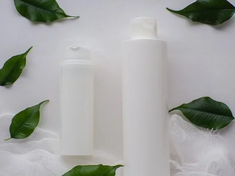 Set of two white bottles and green leaves on white background Foto stock