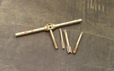 A set of used taps and tap wrench for internal threading. Stock Photos