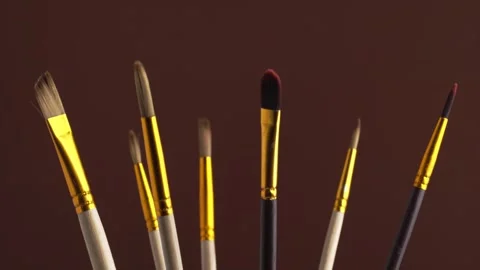 Set of various professional paint brushes rotating on a brown background, m.. Stock Footage 247913204