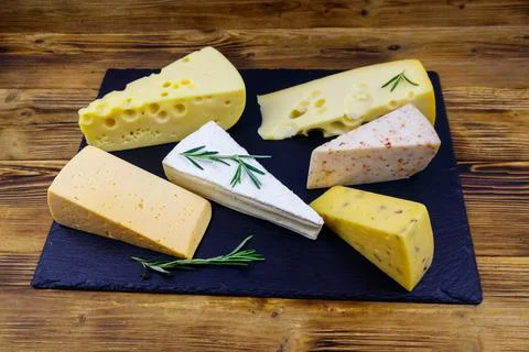 Set of various types of cheese on black slate board on a wooden table Stock Photos