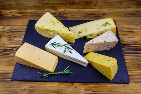 Set of various types of cheese on black slate board on a wooden table Stock Photos