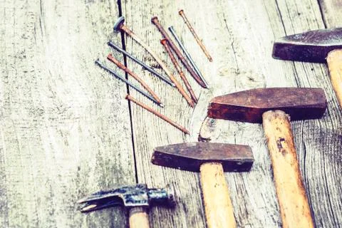 Set of vintage hand construction tools hammers with nails on a wooden backgro Stock Photos