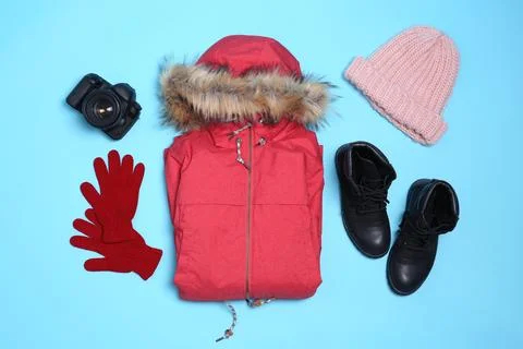 Set of warm clothes and camera on color background, flat lay. Winter vacation Foto stock