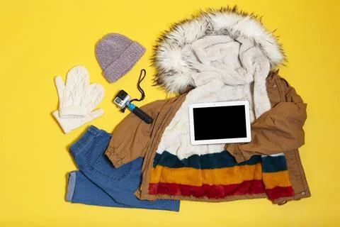 Set of warm clothes and devices on color background, flat lay. Winter vacatio Stock Photos