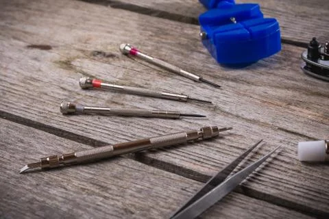 Set of watchmaker tools isolated on a rough wooden board Stock Photos