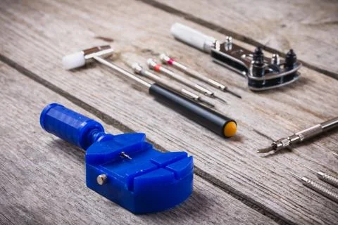 Set of watchmaker tools isolated on a rough wooden board Stock Photos