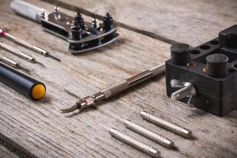 Set of watchmaker tools isolated on a rough wooden board Stock Photos