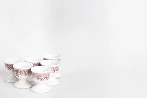 A set of white and red ceramic egg cups with a floral pattern arranged on a Foto stock
