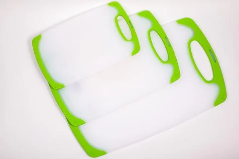 Set of white kitchen cutting boards with green handles for cooking. Stock Photos