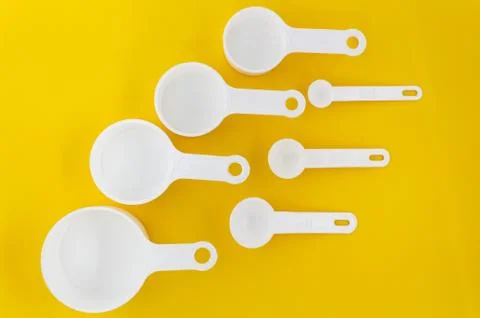 Set of white measuring cups, measuring spoons use in cooking lay on wooden ye Stock Photos