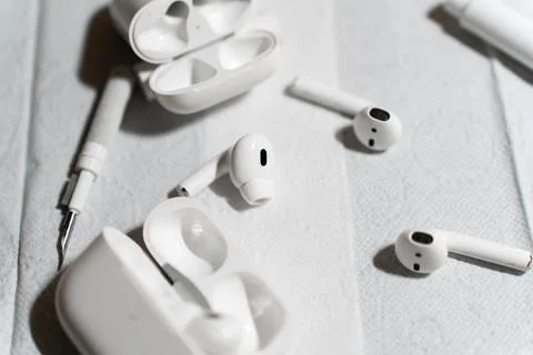 A set of wireless earbuds, charging cases, and cleaning tools laid out on a Stock Photos