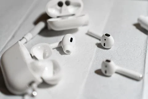 A set of wireless earbuds, charging cases, and cleaning tools laid out on a Stock Photos