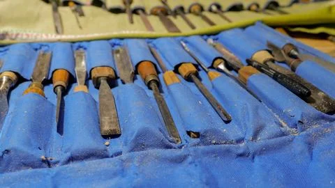 Set of woodcarving chisels and gouges arranged in blue fabric roll with wood Stock Photos