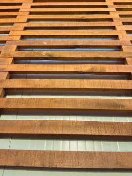 A set of wooden slats creates a pattern on a building's exterior. Blue sky pe Foto stock