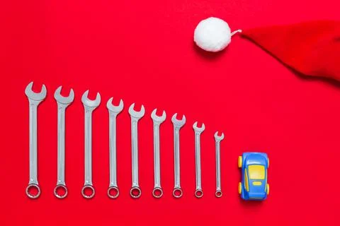 Set of wrenches different size and toy car and santa claus hat on red backgro Stock Photos