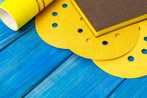 Set of yellow abrasive tools and sandpaper on blue wooden boards Stock Photos