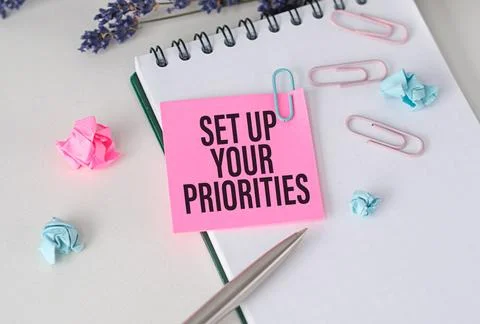 Set Up Your Priorities Text on an Open Notebook in pink paper, Pen, Busines.. Stock Photos