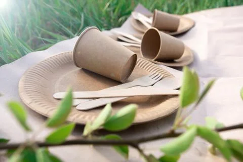 Sets of disposable biodegradable tableware on craft paper in nature. Stock Photos