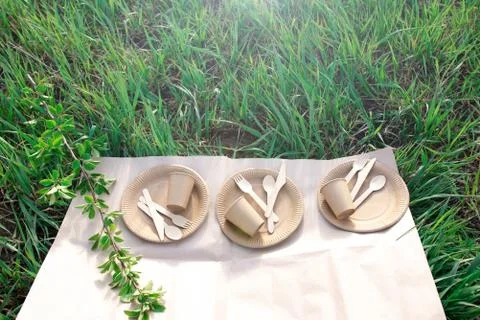 Sets of disposable biodegradable tableware on craft paper in nature. Stock Photos
