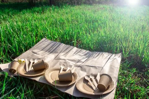 Sets of disposable biodegradable tableware on craft paper in nature. Stock Photos