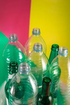 Sets of empty glass bottles and plastic bottles with no label on a vivid gree Stock Photos