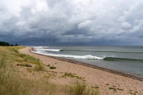 Sets of neat waves breaking on a sandy beach with marsh grass and sand dun... Foto stock